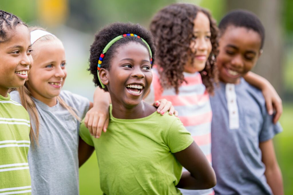 A group of children smiling and hugging each other play in the park