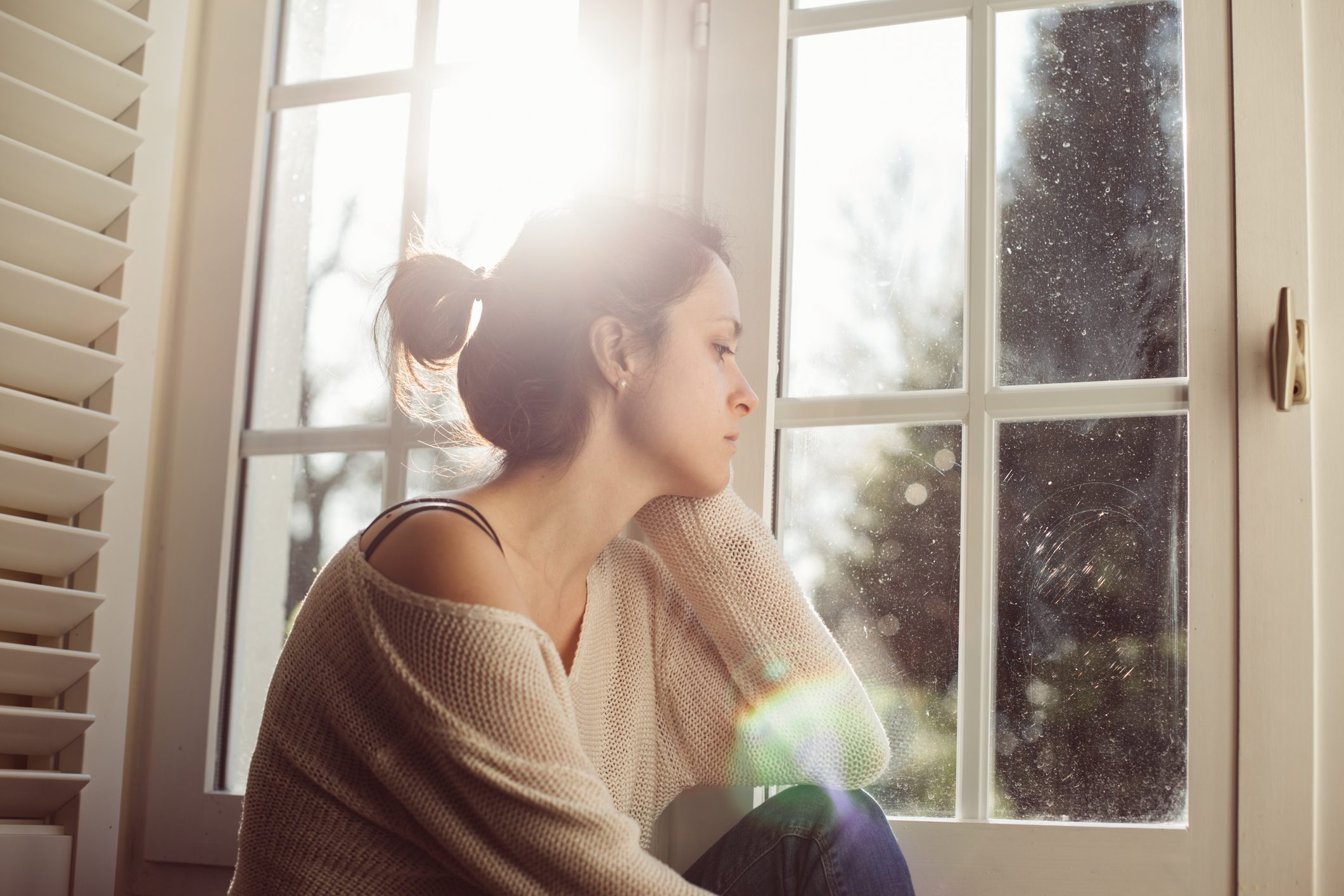 A woman looks out of her window during sunset with melancholia