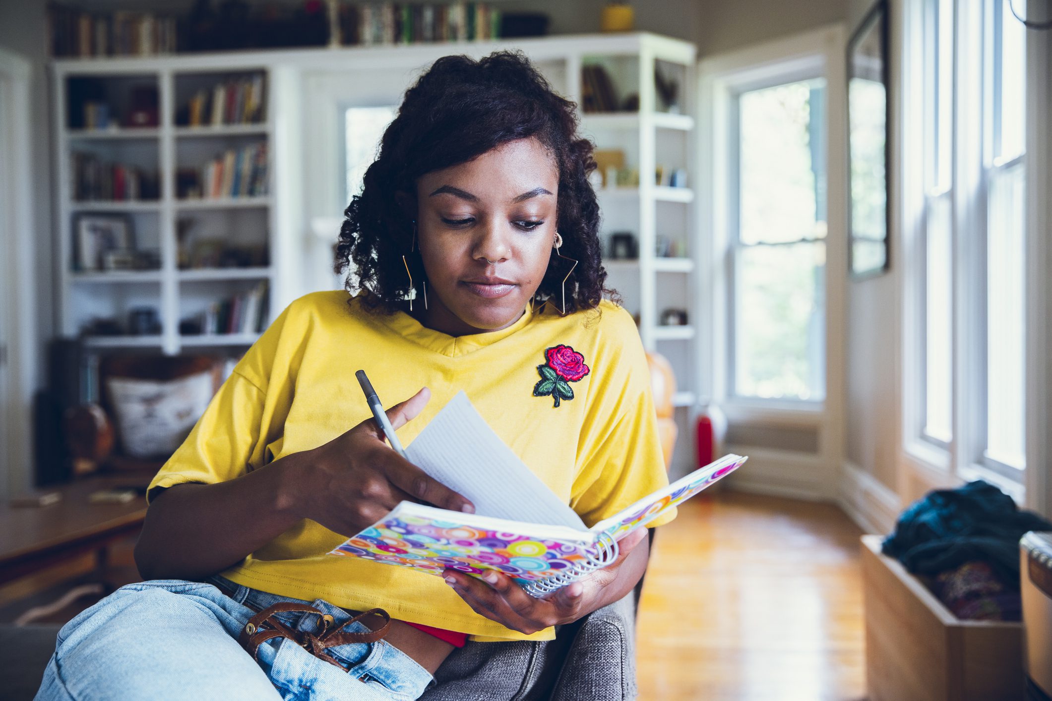 A teenager girl holds open a journal and writes in it