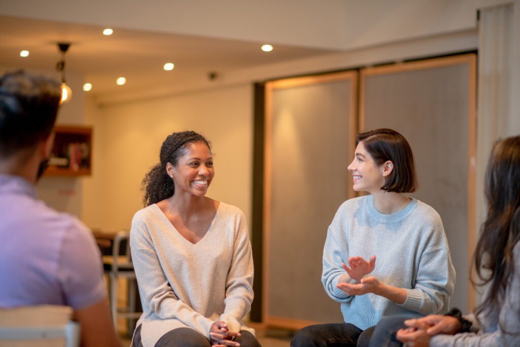 A woman claps and cheers on her peer in group therapy