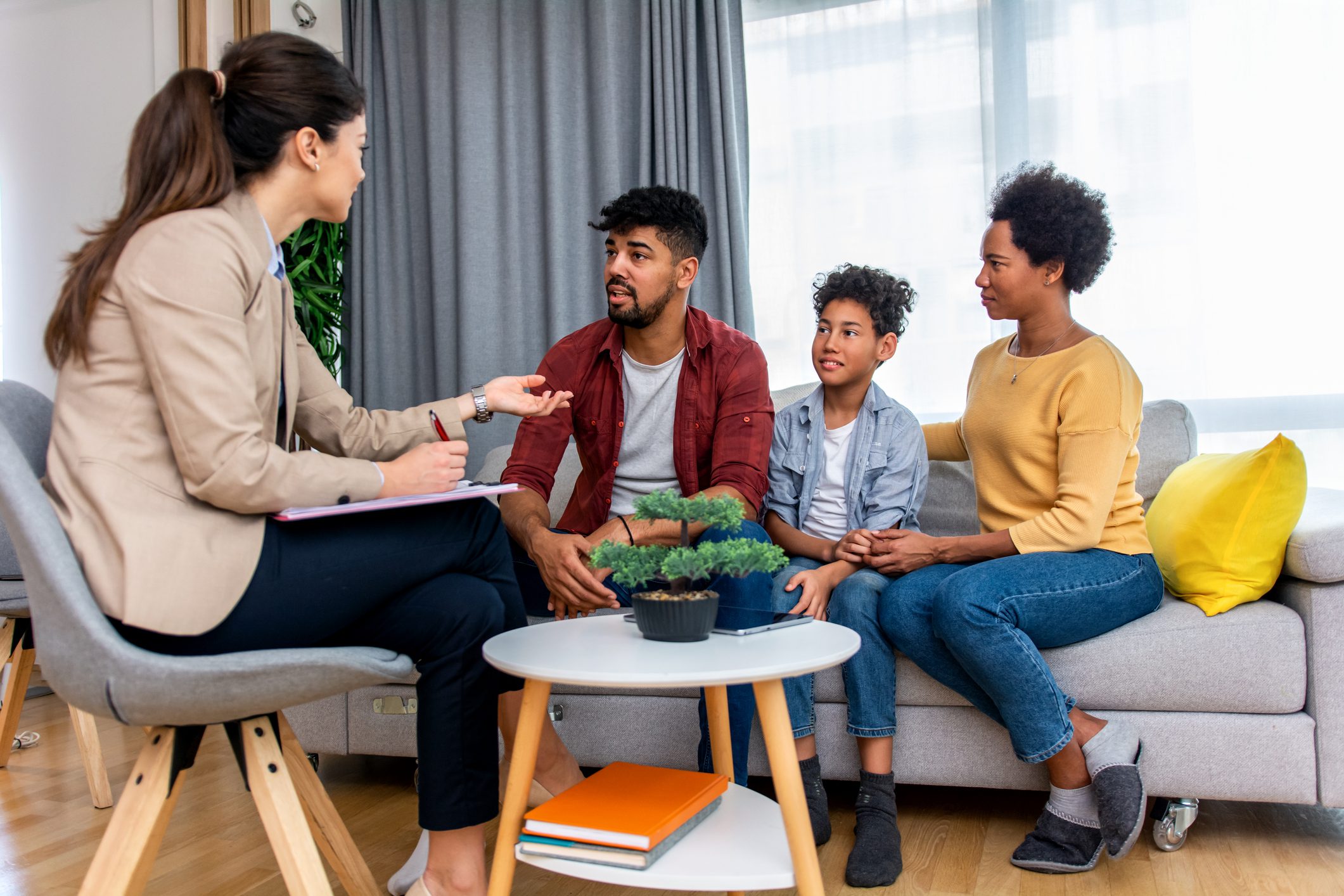 A set of parents and their child sit on a sofa during family counseling