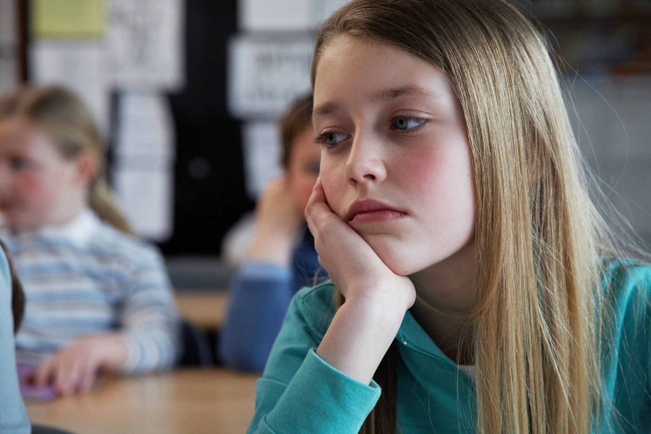 Bored girl leans her head in her hand while distracted in school