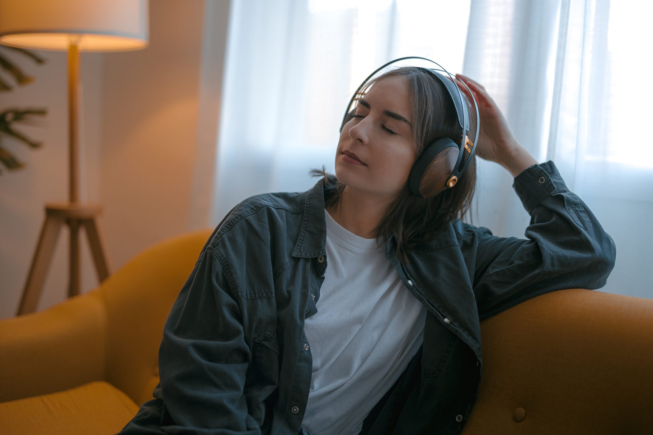 A woman wears headphones listening to music in her living room
